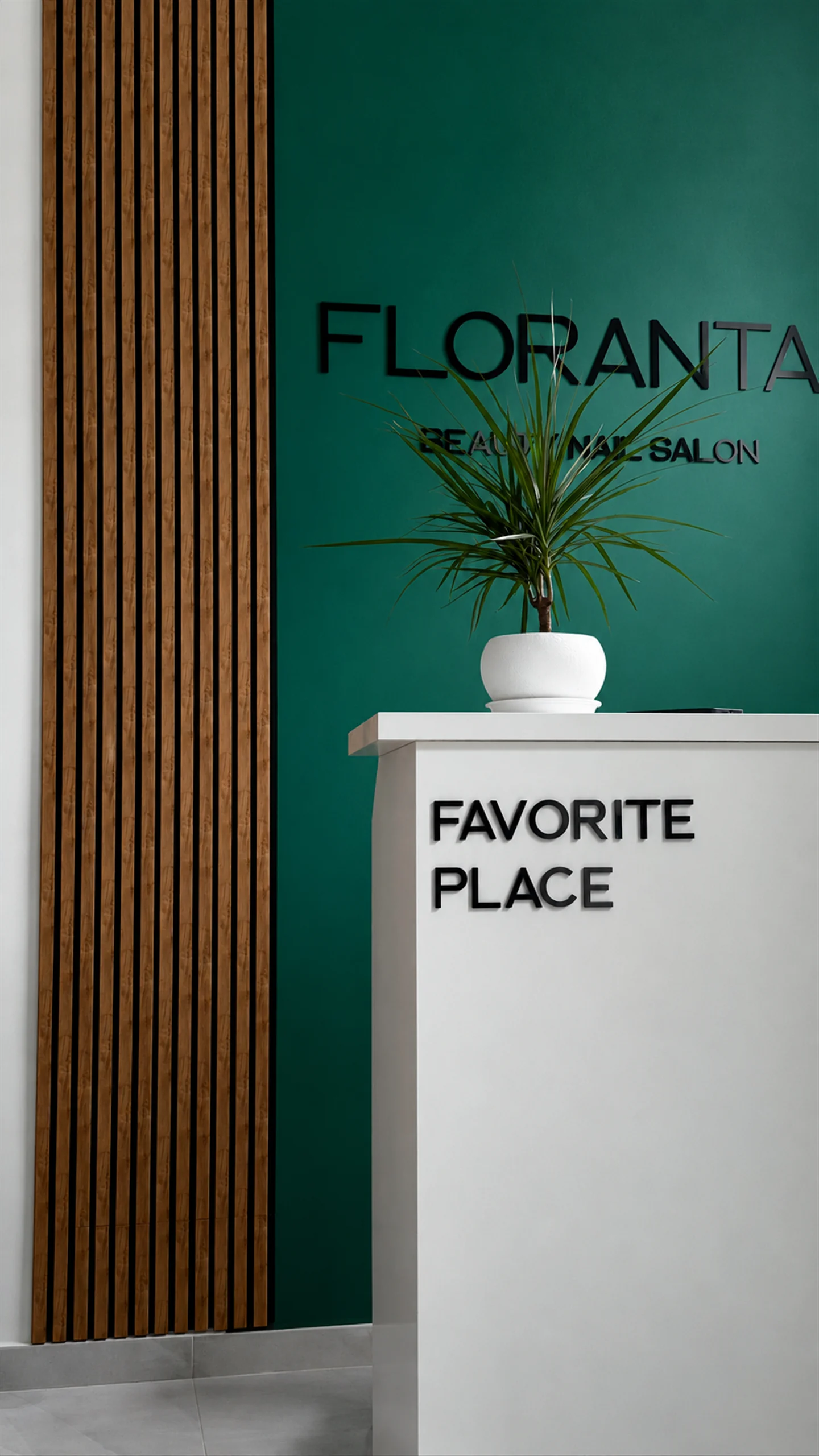Ресепшн салону FLORANTA: зелена стіна з логотипом, дубові рейки, біла стійка